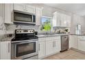 Modern kitchen with stainless steel appliances, granite countertops, and white cabinets at 2812 Tom Brewer Ln, Plant City, FL 33566