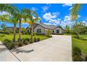 Sprawling home exterior featuring a large driveway, lush lawn, and verdant landscaping with swaying palm trees at 2839 Cordoba Ranch Blvd, Lutz, FL 33559