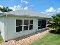 Exterior view featuring a well-maintained exterior, grey roof, and a charming screened-in lanai at 29413 Caddyshack Ln, San Antonio, FL 33576