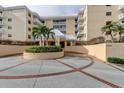 Inviting condo entrance featuring a circular driveway, lush landscaping, and a well-maintained facade at 6600 Sunset Way # 118, St Pete Beach, FL 33706