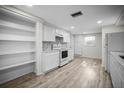 Bright kitchen featuring modern white cabinets, stainless steel appliances, and new wood flooring at 7814 Judith Cres, Port Richey, FL 34668