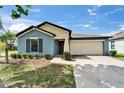 Single-story home featuring a two-car garage, blue paint, and manicured landscaping at 10119 Rose Petal Pl, Riverview, FL 33578