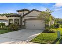 View of a single-Gathering home featuring a two-car garage, beautiful landscaping and modern architecture at 11597 Weaver Hollow Rd, New Port Richey, FL 34654