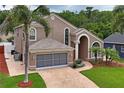 Aerial view of a two-story home with a brick driveway, well-manicured lawn, and lush landscaping at 277 Wood Dove Avenue, Tarpon Springs, FL 34689