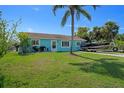 Inviting turquoise home with a well-manicured lawn, a driveway with a boat, and mature palm trees in the yard at 3243 Azalea Dr, Hernando Beach, FL 34607