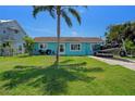 Charming home with a vibrant blue exterior, well-maintained lawn, boat on the driveway, and a palm tree at 3243 Azalea Dr, Hernando Beach, FL 34607