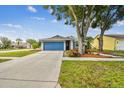 Beautifully landscaped front yard featuring a charming home with a blue garage door at 4108 Woodtrail Blvd, New Port Richey, FL 34653