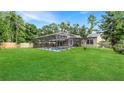 Expansive backyard featuring a screened-in pool area, lush green lawn, and mature trees at 4207 Northwind Ln, Tampa, FL 33624