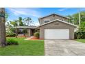 Inviting two-story house featuring a brick facade, attached garage, and lush front yard landscaping at 4207 Northwind Ln, Tampa, FL 33624