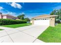 Home's front yard with a long driveway leading to a two-car garage at 4928 Timber Way, Zephyrhills, FL 33542
