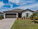 Home with a brick driveway, lush lawn, and vibrant landscaping at 5329 Senza Trl, Palmetto, FL 34221