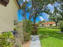 A peaceful outdoor view showing meticulously kept lawn, mature trees, and a glimpse of a refreshing community pool at 5785 Gardens Dr, Sarasota, FL 34243