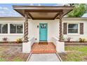 Close-up of home's entrance featuring twisted columns and a vibrant blue front door at 5934 51St N Ave, Kenneth City, FL 33709