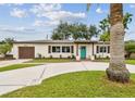 Exterior of home featuring beautiful landscaping, a circular driveway, and a bright blue front door at 5934 51St N Ave, Kenneth City, FL 33709