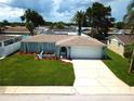 Inviting one-story home with a lush green lawn, colorful landscaping, and a spacious driveway leading to a two-car garage at 7314 Ivanhoe Dr, Port Richey, FL 34668