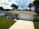 Beautiful single-story home showcasing a green lawn, mature trees, vibrant landscaping, and a convenient two-car garage at 7314 Ivanhoe Dr, Port Richey, FL 34668