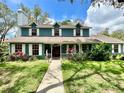 Inviting two-story home with a manicured lawn, mature trees, and a welcoming front porch at 8834 Whispering Oaks Trl, New Port Richey, FL 34654