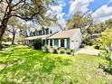 Well-maintained two-story home with lush green lawn, mature trees, and an attached two-car garage at 8834 Whispering Oaks Trl, New Port Richey, FL 34654