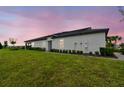 Spacious backyard featuring a lush green lawn and manicured shrubbery under a twilight sky at 10282 Echo Dock Loop, San Antonio, FL 33576