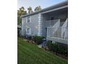 Exterior view of a two-story condo featuring gray walls, white trim, a small yard and access stairs at 12133 Spartan Way # 203, Hudson, FL 34667