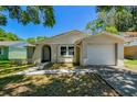 Charming single-Gathering home featuring a one-car garage and an inviting, arched entryway in a tranquil, tree-lined neighborhood at 16138 Manorwood Cir, Tampa, FL 33624