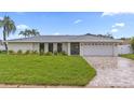 Well-manicured lawn and landscaping highlight this home's brick driveway and white exterior at 1964 Tanglewood Ne Dr, St Petersburg, FL 33702