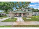 Inviting two-story home with a charming covered front porch, landscaped yard, and an American flag at 205 W Wheeler Rd, Seffner, FL 33584
