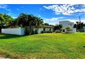Expansive lawn with mature trees surrounds this home, partially enclosed by a privacy fence at 2645 Woodring Dr, Clearwater, FL 33759