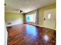 Inviting living room with gleaming hardwood floors, a ceiling fan, and a large window offering plenty of light at 2645 Woodring Dr, Clearwater, FL 33759