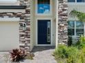 Close-up of the front door highlighting the stone facade and tiled walkway at 38120 Shale Stone Ct, Zephyrhills, FL 33540