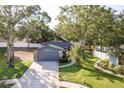 Aerial view of a one-story home featuring a gray garage, stone accents, and a well-manicured lawn with a palm tree at 399 Walnut Ct, Palm Harbor, FL 34683