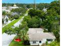 An aerial view of a white home with a shingled roof nestled among lush green trees on a sunny day at 4300 16Th N Ave, St Petersburg, FL 33713