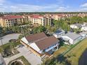 An aerial view of a light gray two-story home with brown roof near a pond and assortment of buildings at 6602 S Sherrill St, Tampa, FL 33616