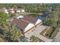 An aerial view of a light gray two-story home with a brown roof and a nearby pond at 6602 S Sherrill St, Tampa, FL 33616