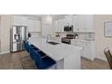 Modern kitchen featuring white cabinets, stainless steel appliances, and a large center island at 17418 Holly Well Ave, Wimauma, FL 33598