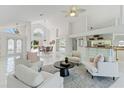 Bright living room with cathedral ceilings, tile floors, modern furnishings, and large windows at 18561 Winding Oaks Blvd, Hudson, FL 34667