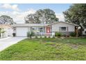 Inviting home with a manicured lawn, red door, white picket fence, and an attached garage at 2005 Jefferson Ave, Dunedin, FL 34698