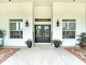 Inviting front porch with double doors, sconces, windows, potted plants, and stylish seating at 28410 Wildlife Ln, Brooksville, FL 34602