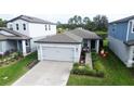 Inviting home featuring a two-car garage, lovely landscaping, and cozy front porch seating at 3329 Fresno Pl, Zephyrhills, FL 33541