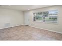 Bright living area with tile floors and ample natural light from a large window and a neutral-toned door at 4414 Royal Oak Ln, New Port Richey, FL 34653