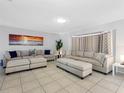 Large living room with neutral-colored couches, tile flooring and a decorative plant at 9109 134Th Way, Seminole, FL 33776