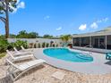 Backyard pool area surrounded by white fencing, lounge chairs and a screen-enclosed patio area at 9109 134Th Way, Seminole, FL 33776