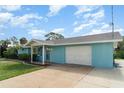 Side view of a light blue single-Gathering home featuring an attached garage and manicured landscaping at 105 E North Branch Rd, Ruskin, FL 33570