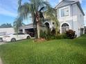 Two-story home with a well-manicured lawn, mature landscaping, and a palm tree in the front yard at 1521 Atami Ct, Wesley Chapel, FL 33544