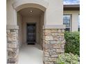 Covered front entry showcasing stone pillar accents and a black front door at 1827 Trillium Blvd, Brooksville, FL 34604