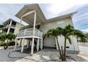 Side view of a charming raised stilt home with stairs leading up to the covered porch at 19111 Whispering Pines Dr, Indian Shores, FL 33785