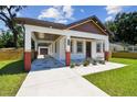 Attractive home showcasing a covered carport, unique gray stone patio, and vibrant flower beds at 1914 E Chelsea St, Tampa, FL 33610