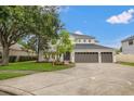 This two-story home features a three car garage, manicured lawn, and mature trees at 21108 Bircholm Ct, Land O Lakes, FL 34637