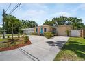 Inviting single-story home with a circular driveway, lush landscaping, and a welcoming bright blue front door at 3115 Bay Ln, Clearwater, FL 33759