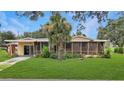 A single-story home featuring a screened-in porch and a lush green lawn with palm tree at 5631 23Rd S Ave, Gulfport, FL 33707